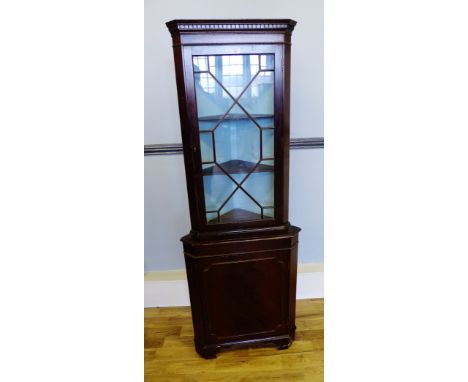 A mahogany corner cabinet with astragal glazed panel door to top above a panel door to base, raised on bracket feet, 66 x 182