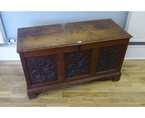 A late Victorian carved oak blanket box having a panel top and three carved front panels raised on bracket feet, 120 x 70cm