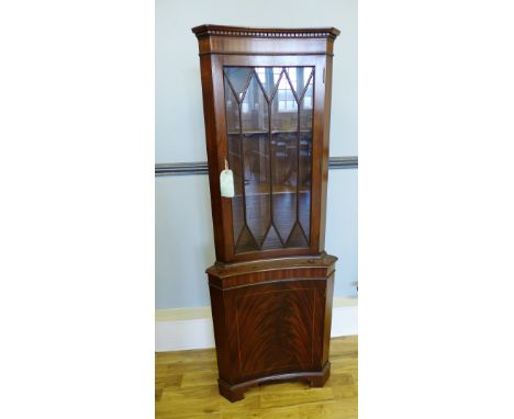 A mahogany corner cabinet with a glazed panel door to top above a panel door to base, raised on bracket feet, 66 x 180cm 