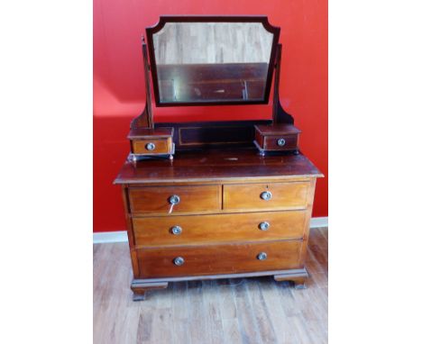 An Edwardian mirror backed dressing chest having a bevel edged mirror and two short drawers over two short and two long drawe