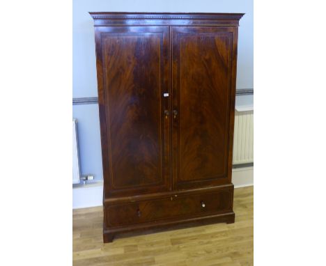 An Edwardian mahogany wardrobe having two panel doors enclosing fitted interior above long drawer raised on bracket feet, 131
