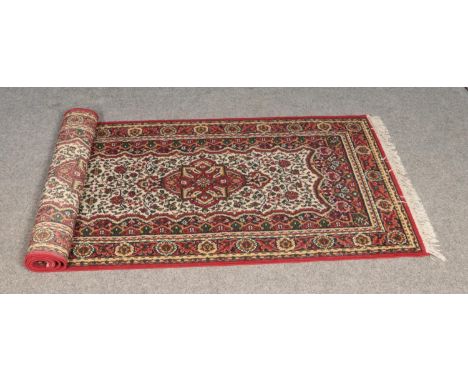 A floral red and cream ground wool runner featured tasseled edges.  