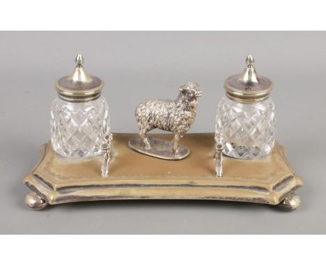 A silver plate inkwell stand with two cut glass inkwells featuring central figure of a sheep and pen holder formed as fence p