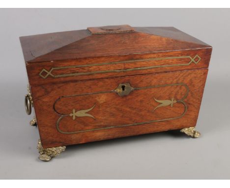 A Regency tea caddy of sarcophagus form. With cut glass bowl, brass lion paw feet, inlaid brass detail and carved motif to li