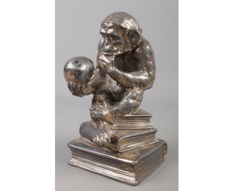 A white metal table lighter formed as a monkey holding a skull. 16cm.  