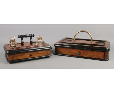 Two mahogany and ebonised desk tidies with lower pen drawers; the smaller one complete with two inkwells and fountain pens.  