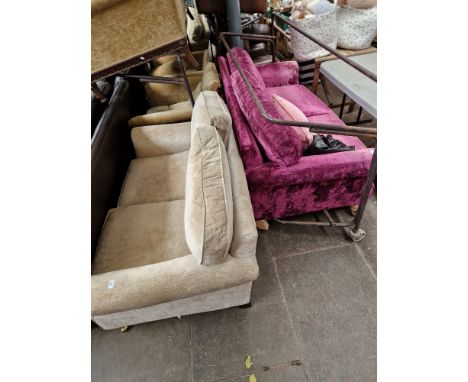 A two seater sofa upholstered in purple velvet together with a cream two seater sofa.  