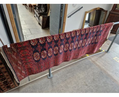 A vintage Middle Eastern Bokhara style wool carpet, red ground, 197cm x 128cm (approx).