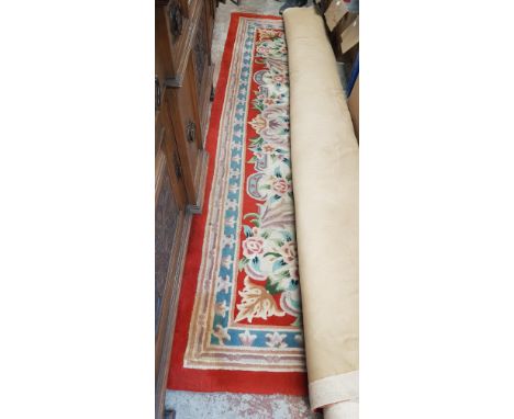 A Chinese wool carpet, red ground decorated with flowers, width 272cm.