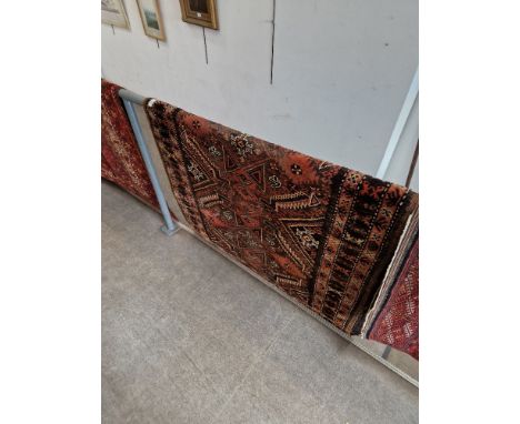 A vintage Middle Eastern wool carpet, red ground, geometric design, 200cm x 110cm (approx).