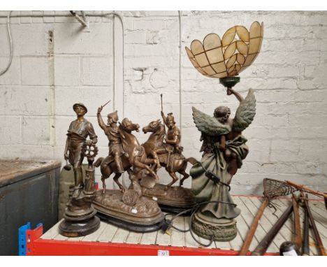 A figural lamp and three spelter sculptures comprising a pair on horseback and one entitled 'Le Mechanicien'.  