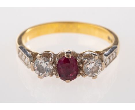 An 18ct ruby and diamond ring, the oval cut ruby set between two brilliant cut diamonds, estimated to weigh 0.30 carats total