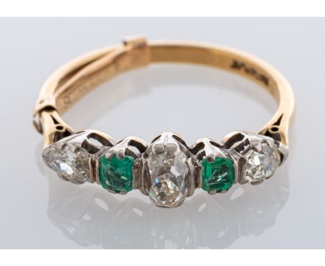 An emerald and diamond five stone ring, claw set with an old mine claw set diamond to the centre, two cushion shaped emeralds