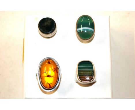 An amber and white metal dress ring; two malachite type mounted white metal rings and another