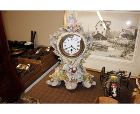 A continental porcelain mantel clock with floral encrusted decoration - minor chips