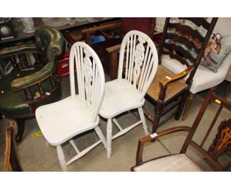 A pair of white painted stick and wheel back dining chairs 