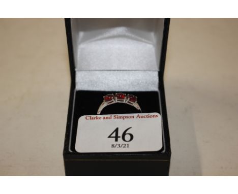 A white metal ring set three red stones