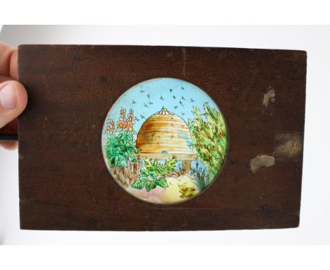 A 19th century magic lantern slide, hand painted colour image on glass of a beehive with rotating bees on separate glass slid