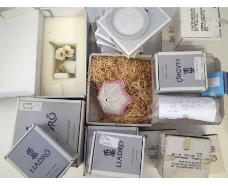 Fourteen Lladro boxed spares to include umbrellas and flowers, also six small dishes.      From the shop clearance of Stonier