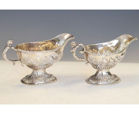 Matched pair of George II/George III silver pedestal cream boats, each having a figural scroll handle, gadrooned rim and late