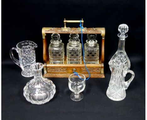 Late Victorian carved oak tantalus with plated mounts and a fall front, enclosing 3 square cut glass decanters, each with a f