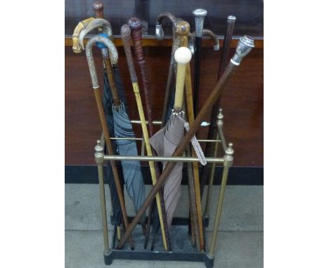 A collection of sixteen walking sticks and umbrellas, three with silver tops, one with 18ct gold decoration and a brassumbrel