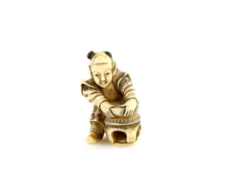 A stained ivory netsuke of a boy, lifting a stone from a table, 19th or 20th CenturyProvenance: The Property of a Lady. From 