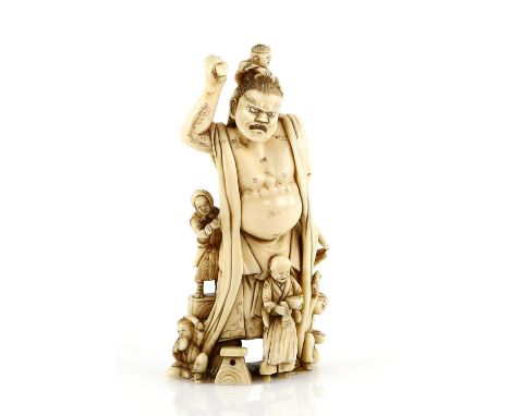 An ivory okimono carved as a huge Temple Nio surrounded by five pilgrims or restorers, one boy combing the Nio's hair; 11 cm 