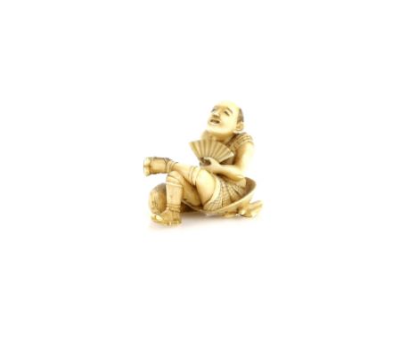 A stained ivory netsuke of a traveller seated on a bundle, and holding a fan with his left hand; the base of the netsuke carv