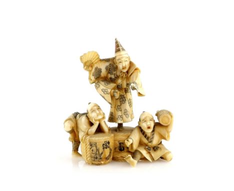 A stained ivory okimono carved as a  Manzai, or other, dancer on top of a Sake jar beside two other men, one using a bucket a