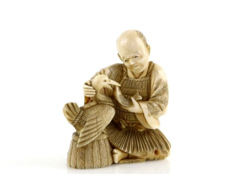 A stained ivory okimono, carved as a cormorant fisherman feeding his bird, nearly 8 cm high, 19th or 20th CenturyProvenance: 