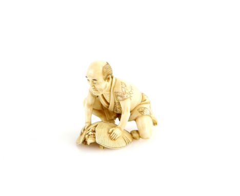 A stained ivory netsuke of a kneeling man trapping an Oni in a parody of Shoki, two kanji, 19th or 20th Century.Provenance: T