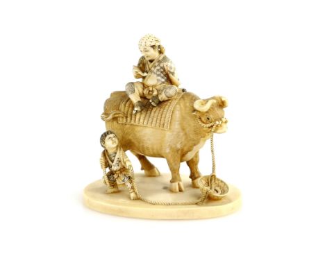 A stained ivory okimono carved as a farmer with his pipe on the back of a large ox being led by a farm boy, nearly 7 cm diame