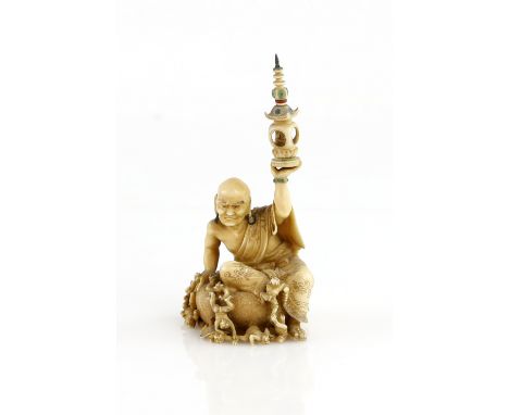 A stained ivory okimono, carved as an Arhat, seated in a large alms bowl and looking fiercely down at a number of small Oni, 