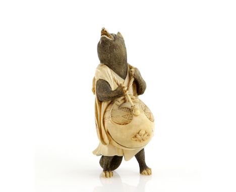 A stained ivory okimono of a standing badger, beating a large mokugyo with a single stick, 9 cm high, signed Ryusai, Meiji Pe