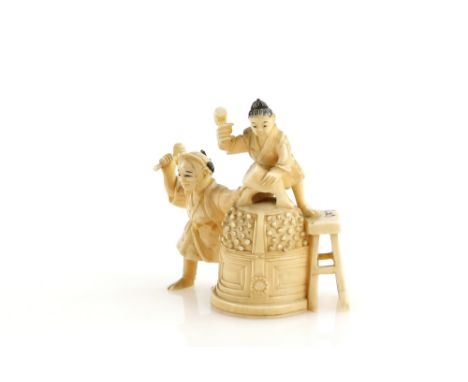 A stained ivory okimono, carved as two artisans working on the construction of a massive Bonsho, 6.5 cm high, 19th or 20th  C