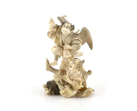 A stained ivory okimono, carved as a Tengu holding up a rabbit and frightening a hunter with his Teppo and Monkey, 13 cm high