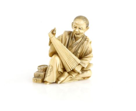 A stained, sectional ivory okimono of an umbrella and parasol maker, 9 cm high, Meiji PeriodProvenance: The Property of a Lad