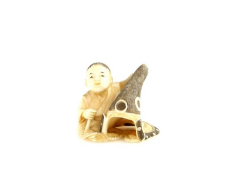 A stained ivory netsuke carved as a boy seated beside a Kato Kiyomasa style, Nagaeboshi helmet, 20th CenturyProvenance: The P