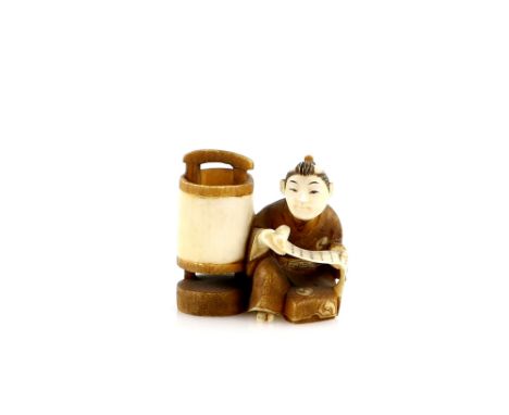 A stained ivory netsuke of a seated boy reading a makemono by lamplight, signed Kogyoku, 20th CenturyProvenance: The Property