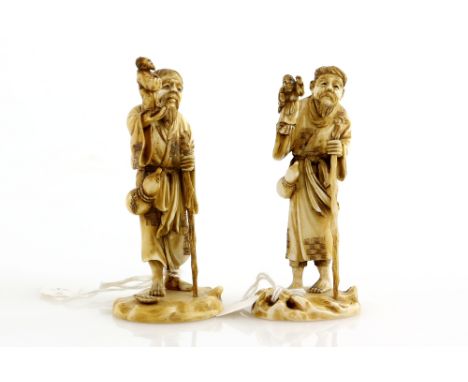 A pair of small ivory okimono; each one carved as a Sennin holding a gnarled staff and wearing a gourd flask whilst holding a