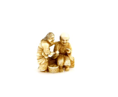 A stained ivory netsuke carved as the Momotaro Story, and depicting an old man and women together, sitting on a log and exami