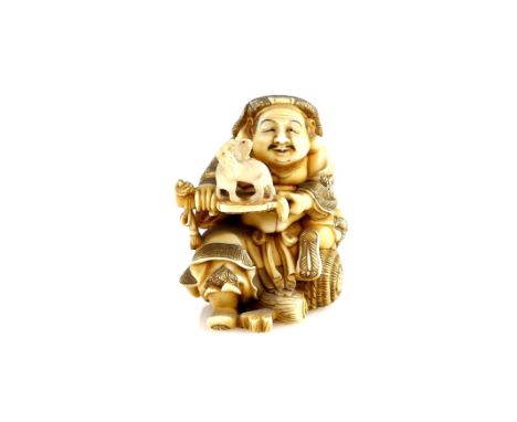 A stained ivory netsuke or small okimono of Daikoku with a pair of rats, seated on his bale of rice, and with his large hamme
