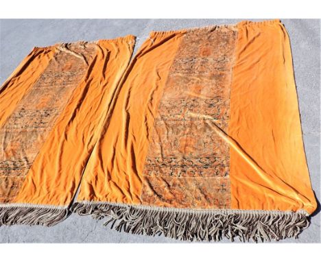 A PAIR OF BURNT ORANGE VELVET CURTAINS, WITH CENTRAL FIGURED PANELS with metallic thread work, and bullion fringing 260cm dro