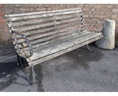 A WROUGHT IRON FRAMED GARDEN BENCH with scrolling arms and weathered slats 150cm wide