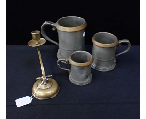 THREE PEWTER PUB MEASURES with brass rims, 19th century, and a piano candlestick