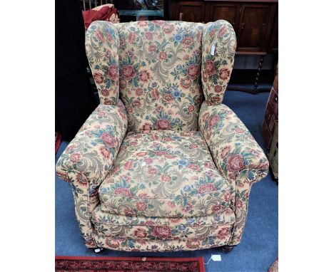 A 1920S COUNTRY HOUSE WING ARMCHAIR on bun feet upholstered in tapestry fabric