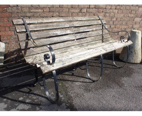 A WROUGHT IRON FRAMED GARDEN BENCH, WITH CENTRAL SUPPORT scrolling arms and weathered slats 168cm wide