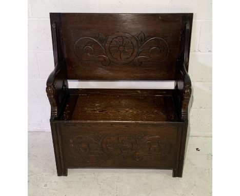 An oak monks bench with carved arms, fold down top and lift up seat