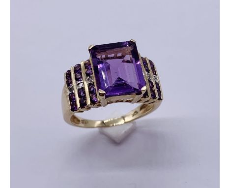 A large 10ct gold ring set with a central amethyst with diamond and amethyst shoulders